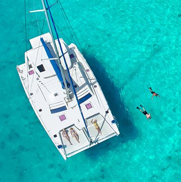 Aerial view of catamaran with people snorkeling 